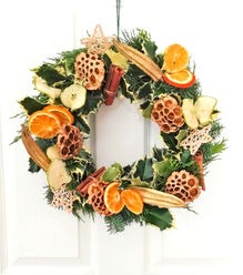 Christmas wreath on a door with oranges and gold lotus seen heads and evergreen foliage