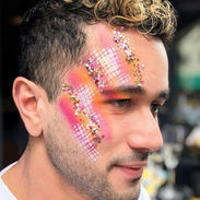 Man with orange pink and white paint and glitter on the side of his face