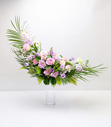 Crescent shape flower arrangement with pink, and lilac flowers