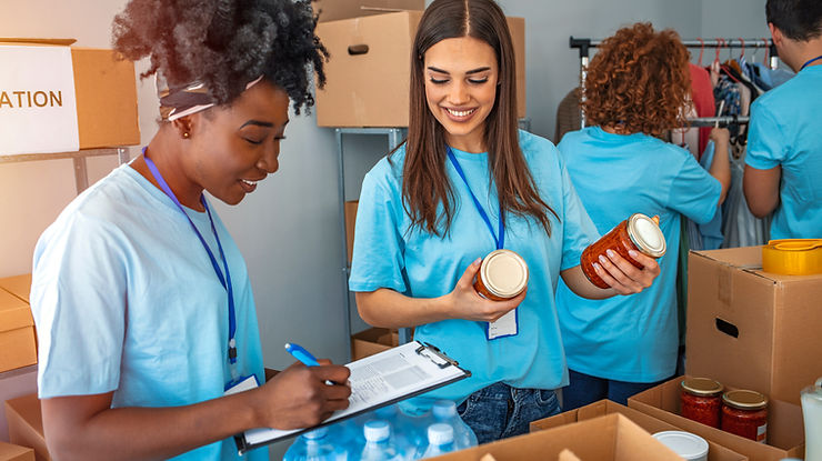 Group of people working in charitable foundation. Happy volunteer looking at donation box