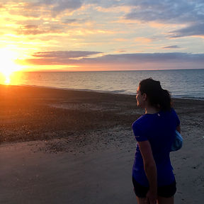 Woman watching the sunset over the ocean from a beach
