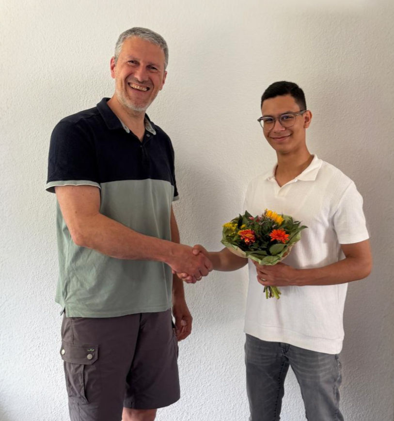 Links Frank Heilf und rechts Diego Schön mit einem Blumenstrauß in der Hand. Beide geben sich die Hand