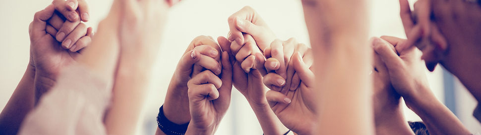 Group of mixed races in unity holding their hands in a circle raised up high