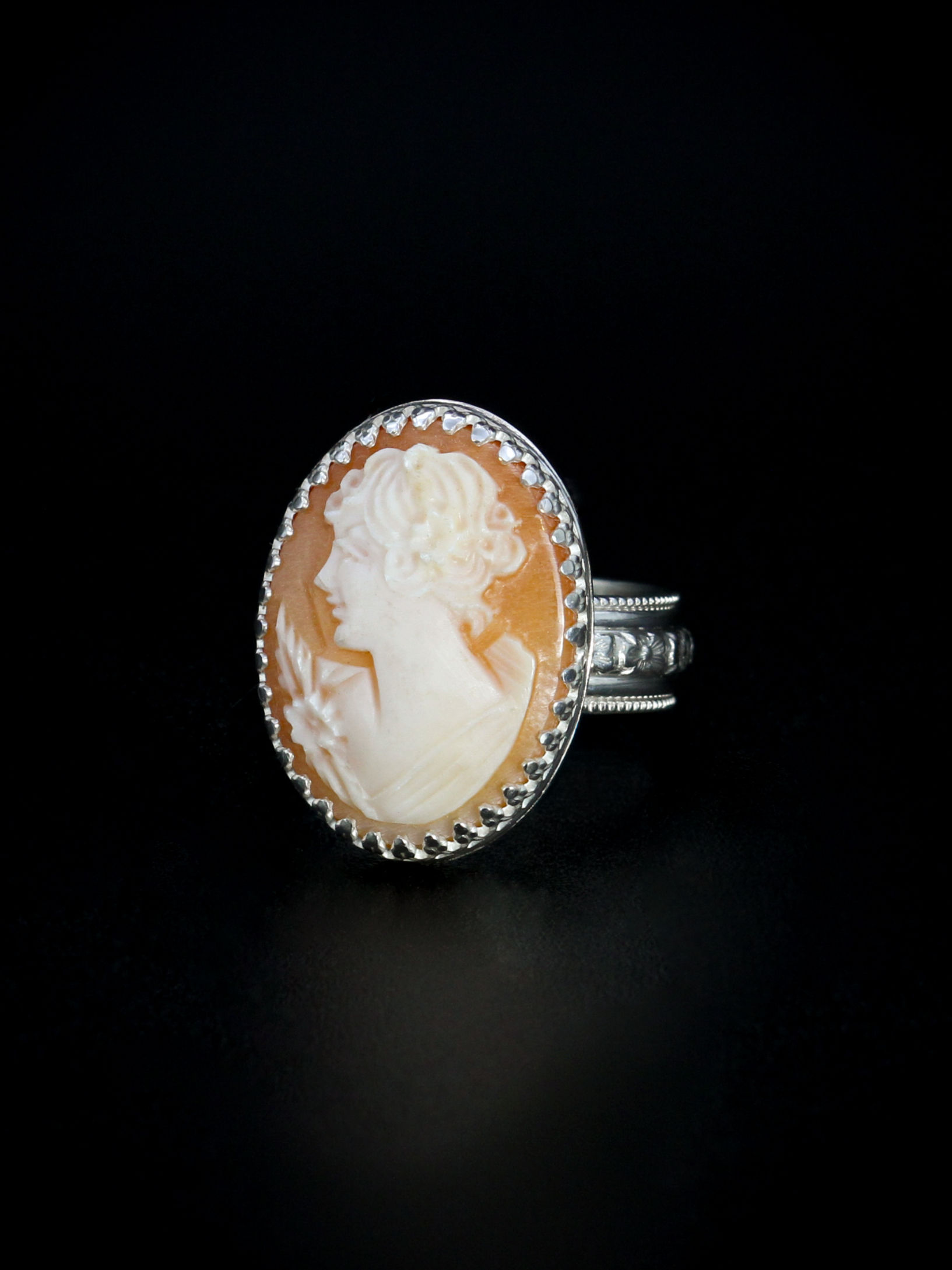 Peach colored stone with carving of the profile of a woman set in detailed sterling silver ring
