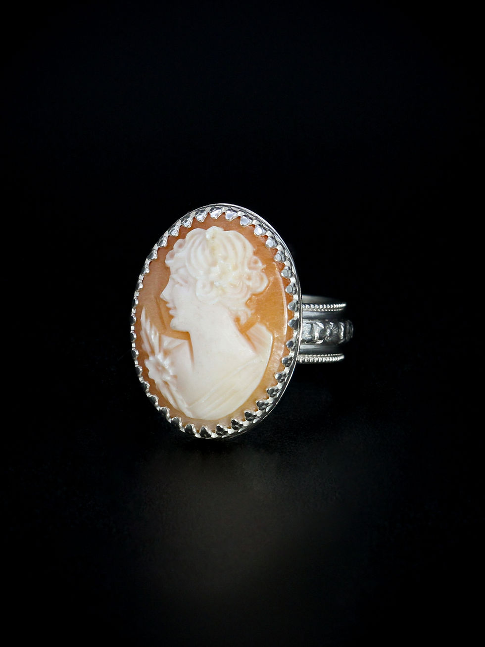 Peach colored stone with carving of the profile of a woman set in detailed sterling silver ring