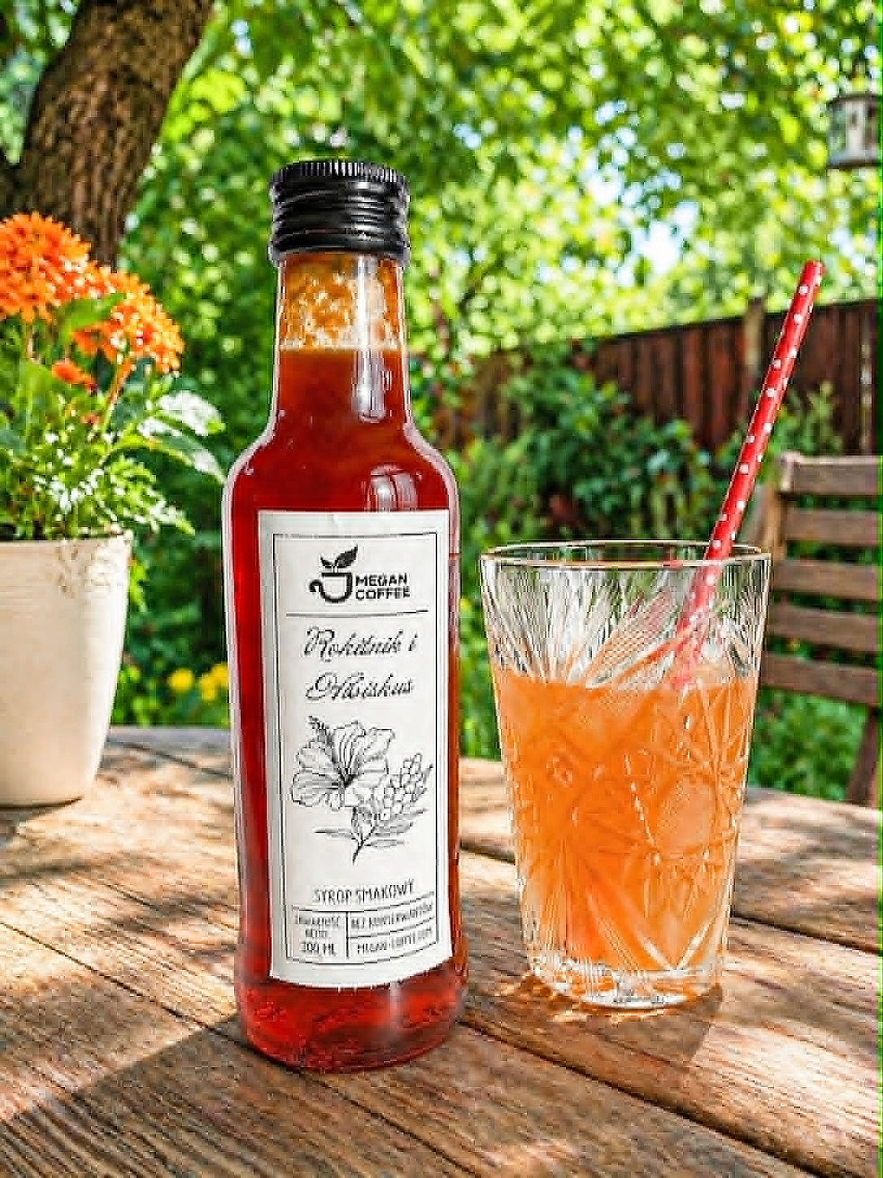 Miniatura: Szklana butelka z syropem z rokitnika i hibiskusa i szklanka z lemoniadą na stole w ogrodzie