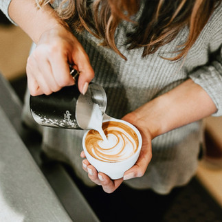 kobieta robi latte art na kawie w białej filiżance