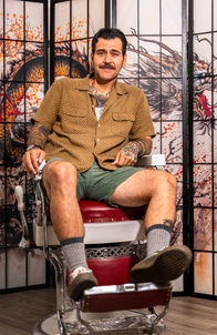 Barber seated in chair at Good Times at The Hideout Barbershop.