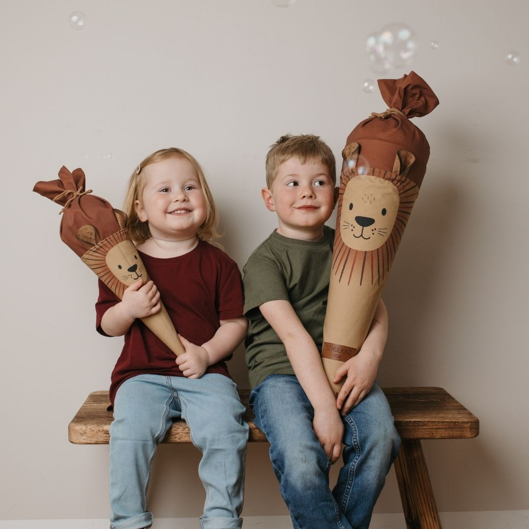 Zwei Geschwister halten Mafee Schultüte und Geschwistertüte Löwe – personalisierte Stoffschultüten zur Einschulung