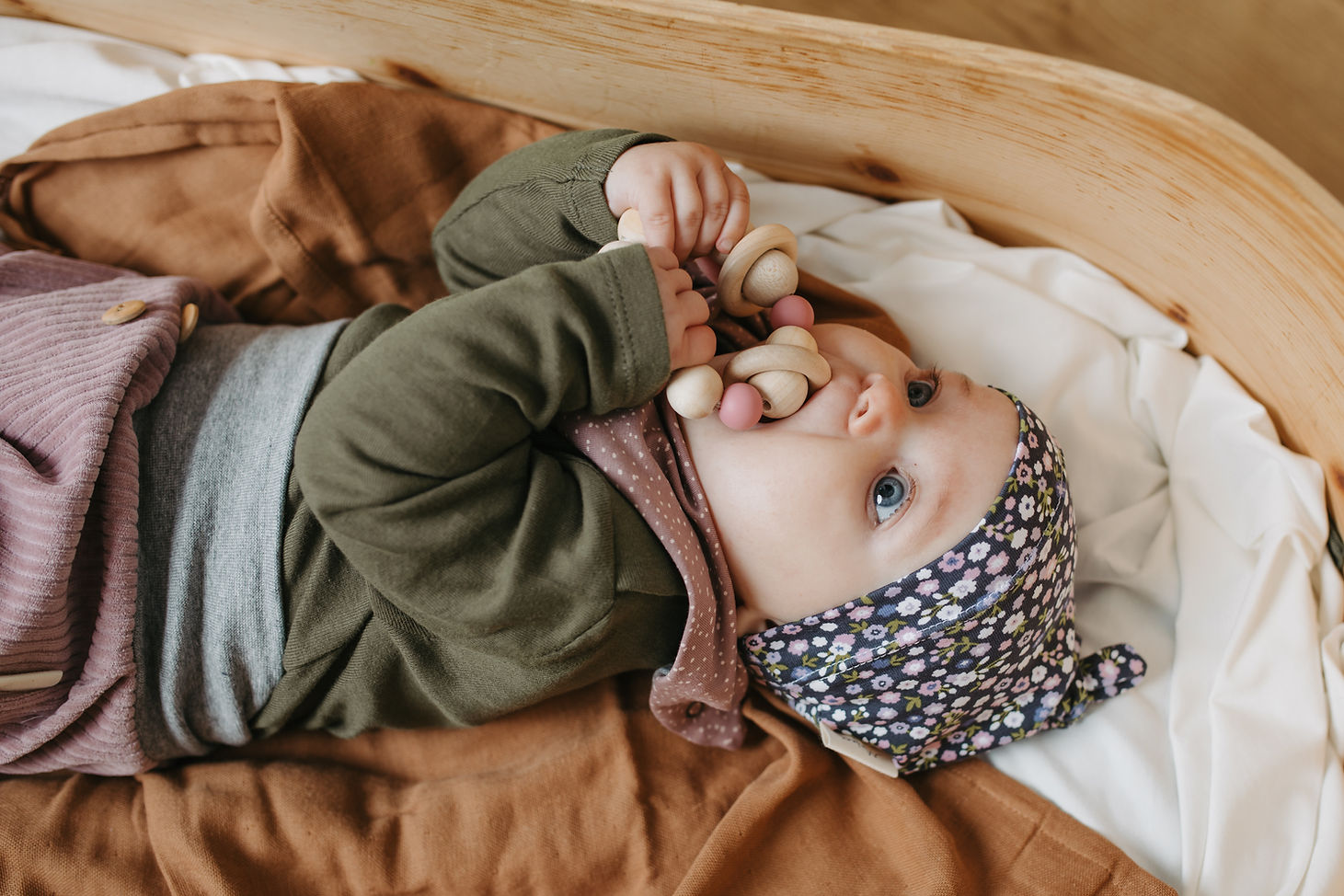 Baby hält Greifling aus Holz von Mafee und nimmt ihn in den Mund