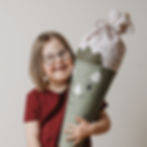 Mädchen hält personalisierte Schultüte Dino aus Stoff von Mafee und lächelt in die Kamera