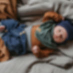 Baby liegt am Rücken mit Babyhose und personalisiertes Babyhalstuch aus Biobaumwolle von Mafee