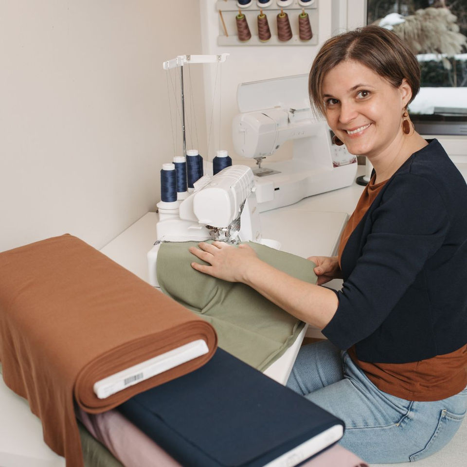 Daniela von Mafee sitzt an der Nähmaschine und näht eine personalisierte Babydecke aus Biobaumwolle