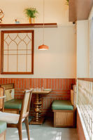 Miri Mary - dining room with exposed brick wall, banquette seating and arched window screens