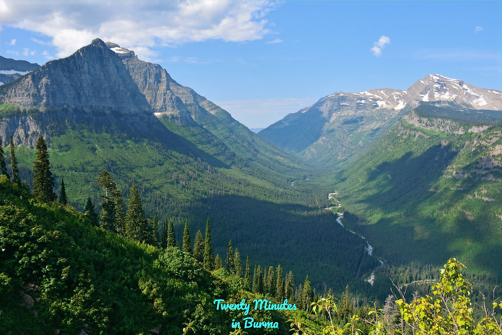 Mountain landscape with green valleys and snow-capped peaks under a blue sky. Glacier National Park, Montana