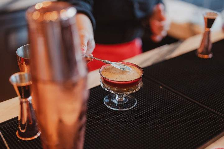 Bartender finishing a mocktail beside copper bar tools