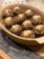 Lamb stuffed mushrooms in yellow le cruset on cutting board with black board and chalk ingredients