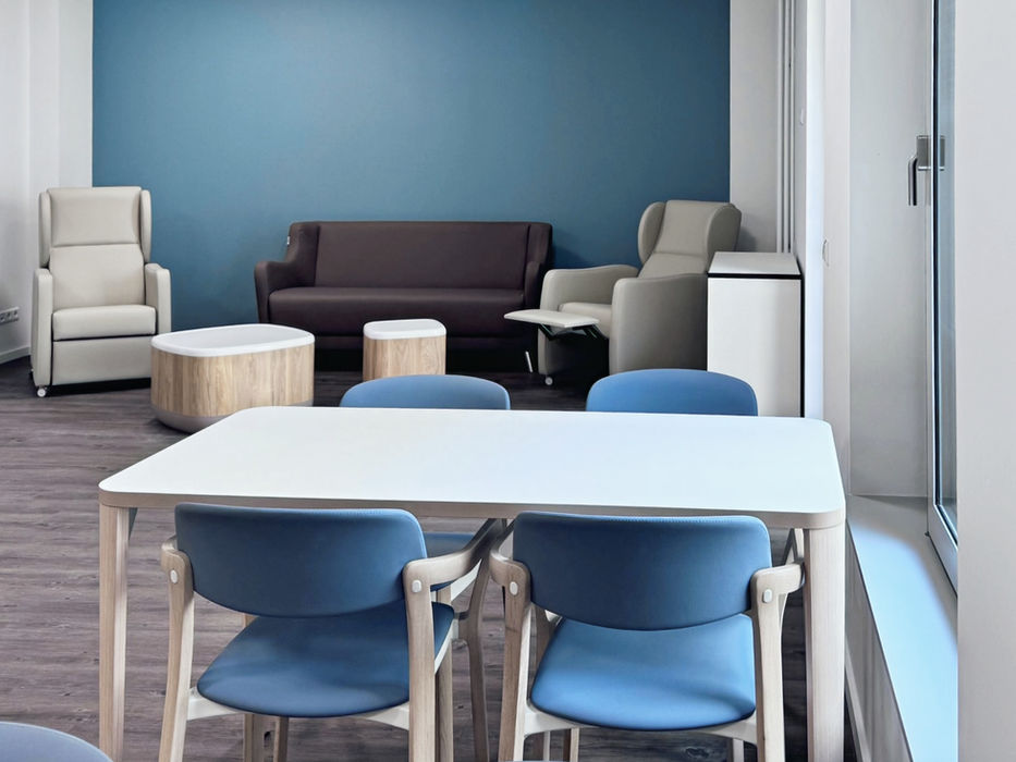 Speise und Aufenthaltsraum mit blauer Wand und blauen Stühlen, sowie beigen Sofas