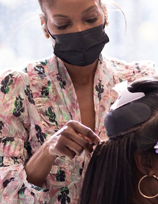 Professional stylist demonstrating hands-on hair extension technique.