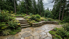 Natural stone patio with seat wall stone steps and native plantings on a residential property in Victoria BC showing integrated hardscape design for coastal climate