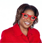 A woman wearing a red collared top and red reading classes with a friendly smile