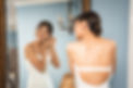 Bride puts earrings on with mirror