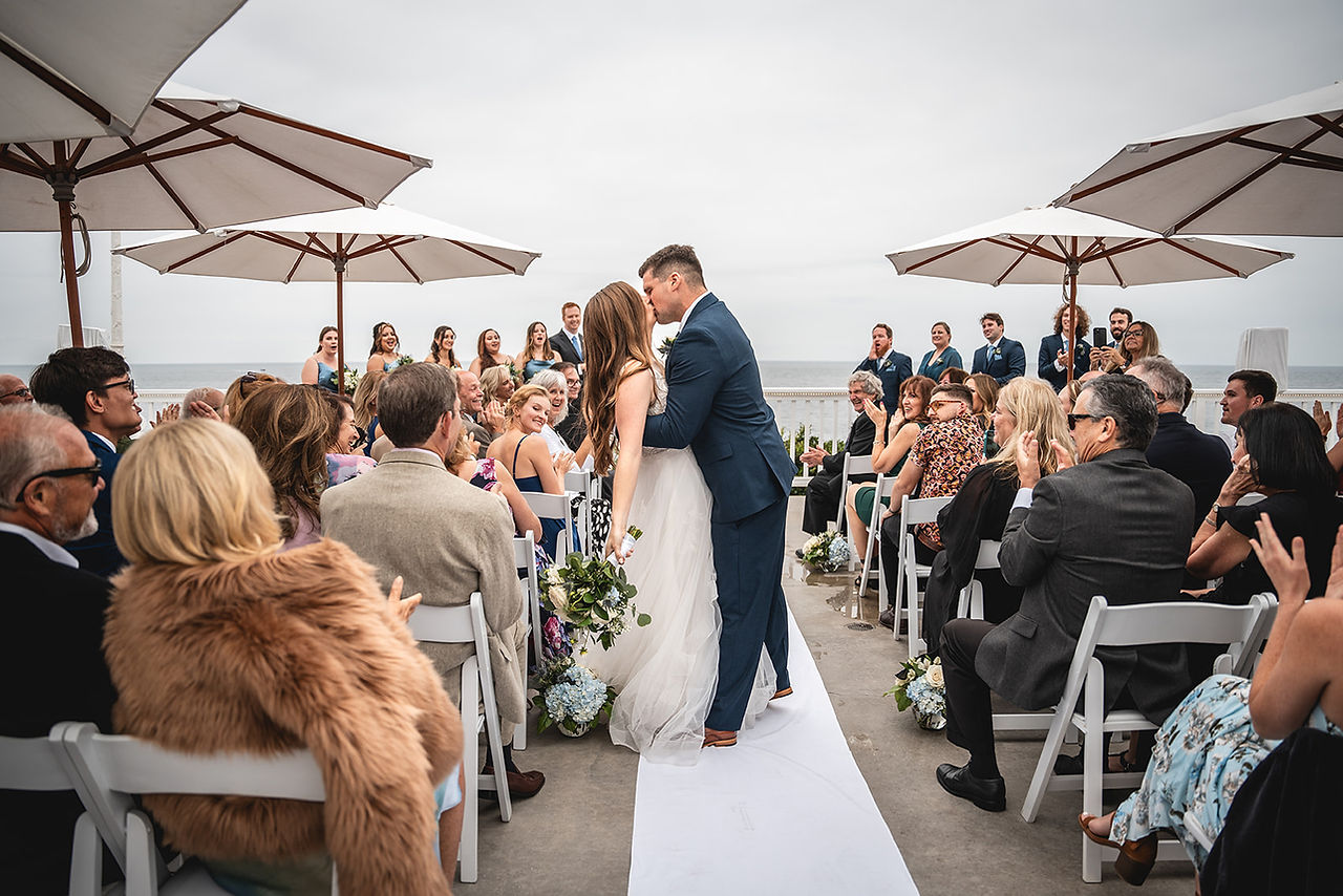 Groom dips and kisses bride in aisle at Wedding Ceremony at Occasions at Laguna Village in Laguna Beach photo by Paper Birch Collective, California Wedding Photographer in Orange County
