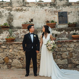 Newly weds hold hands and look at each other for Wedding photoshoot at Mission San Juan Capistrano by Paper Birch Collective, SoCal Wedding Photographer in Orange County, California