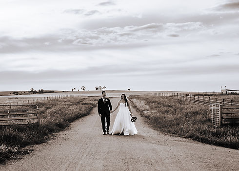 A bride and groom walking up a dirt road surrounded by paddocks. Rural Wedding Photographer