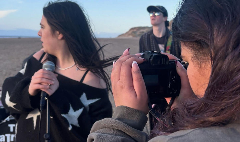 Young creatives filming a music video on a beach.