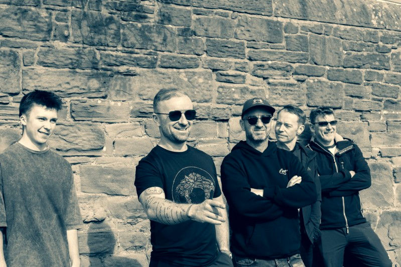 The Harmonix band members posing in front of a stone wall.