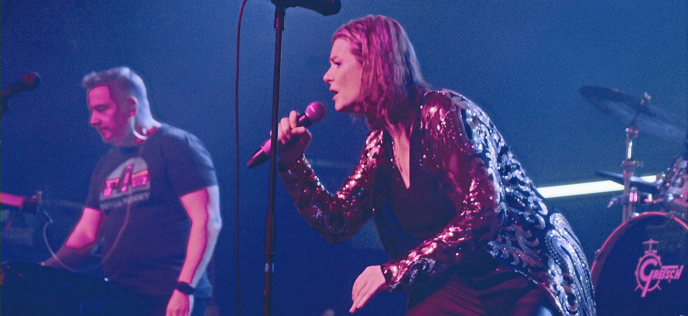 Female singer in sequined jacket performing on stage
