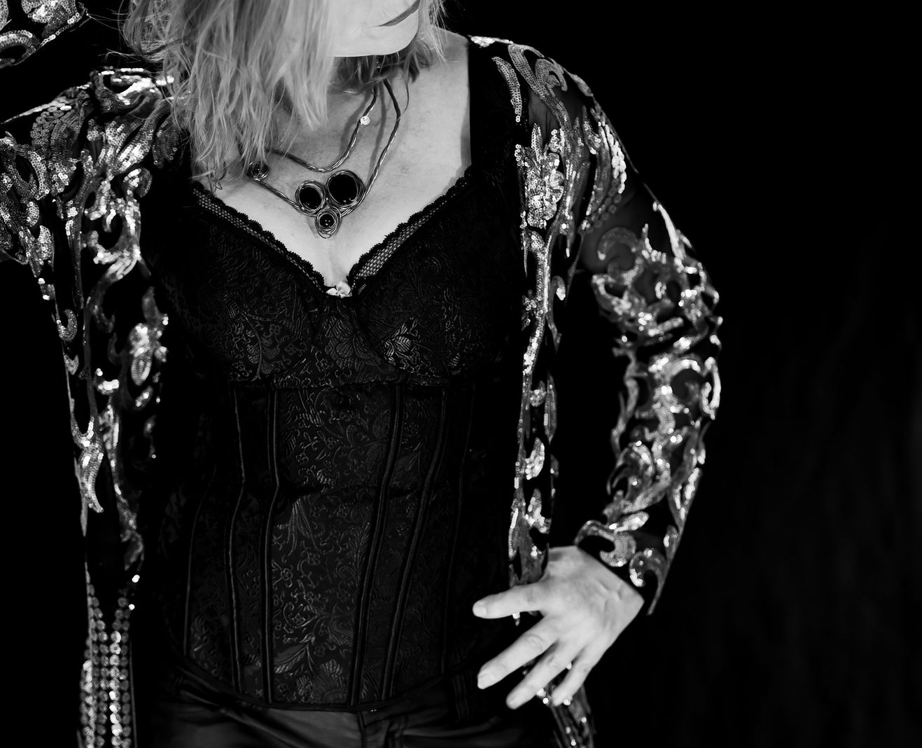 Woman in patterned cardigan and black top posing for AudioGenika