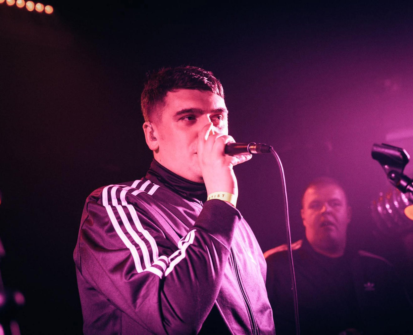 Deltamanic performing live on stage with a microphone.
