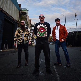 Three musicians from an independent artist roster in an alley.