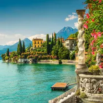 Colorful villas and gardens along Lake Como, Italy, with mountains in the background — symbolizing the dream lifestyle for U.S. retirees.