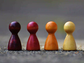 Vier Figuren für ein Spiel mit den Farben dunkelrot, kaminrot, orange und gelb.