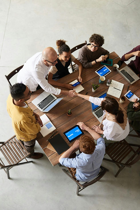 Team collaborating around a wooden table with laptops, tablets, and notebooks, symbolizing creative and innovative web development and design solutions tailored for seamless IT integration and business growth.