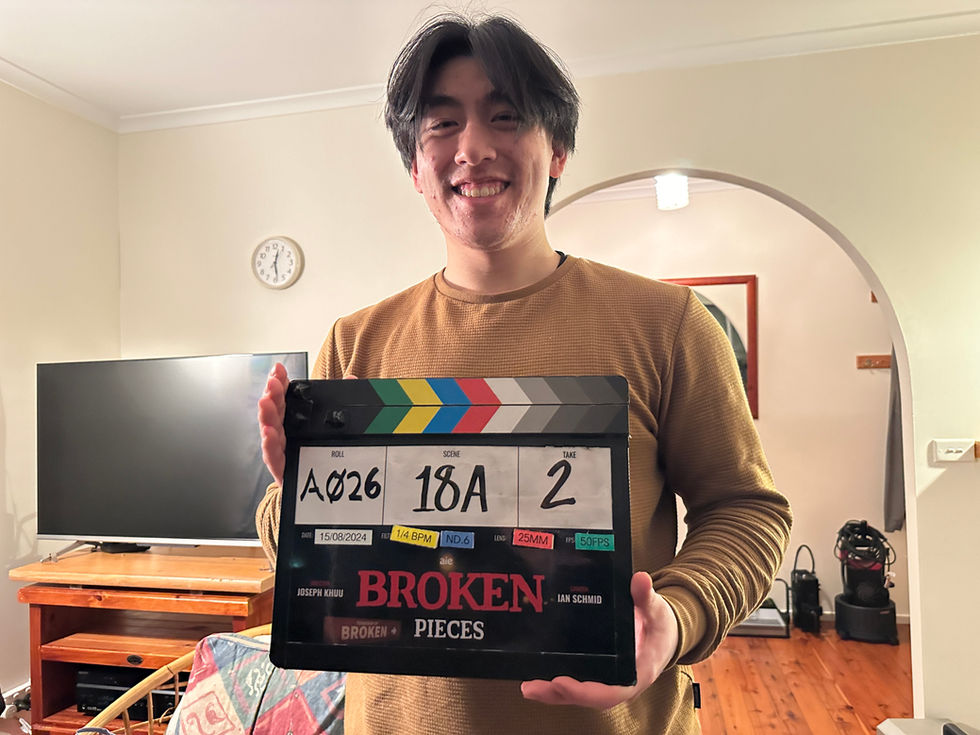 Person holding a film clapperboard, smiling indoors.