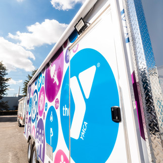 18ft Carefree Fiesta vinyl patio awning deployed on the YMCA concession trailer with exterior LED li