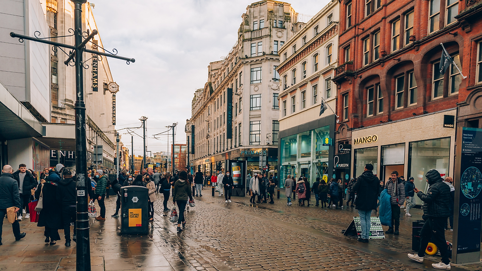 Busy cobblestone street in Manchester with shoppers.