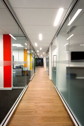 Vue sur le corridor menant aux espaces bureau du Centre de Services d'Audi à Québec. L'ascension de ce corridor est rythmé par des pans de murs colorés.