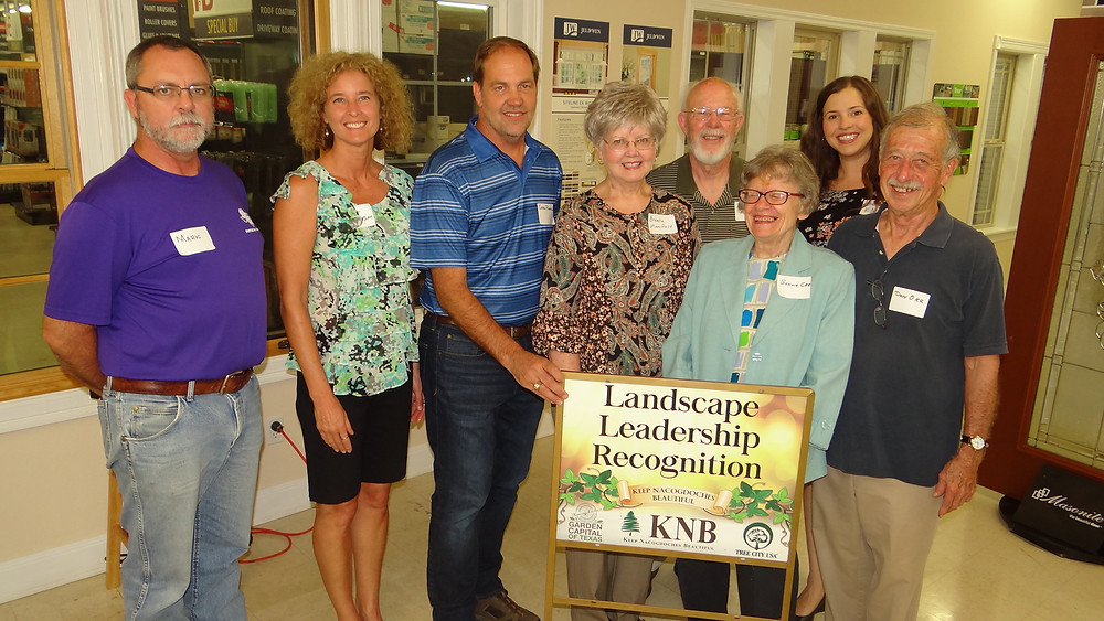 The Pattersons pose for a photo with the Landscape Leadership Award along with their extended family and friends, Keep Nacogdoches Beautiful members, and Garden Capital of Texas Committee members. (From left to right) Mark Holl, Cindy Patterson, Greg Patterson, Brenda Mansfield, Harry Mansfield, Bonnie Orr, Katie Blevins, and Don Orr.