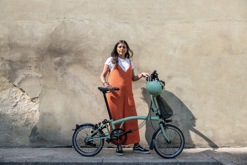 Frau mit mintfarbenem Brompton-Faltrad vor Mauer