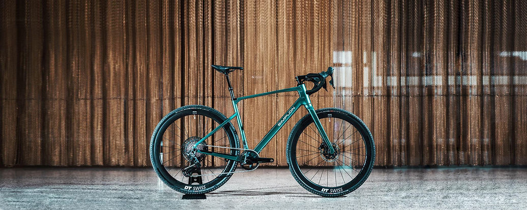 Tiefgrünes Gravelbike der vor HolzfassadeMarke Simplon