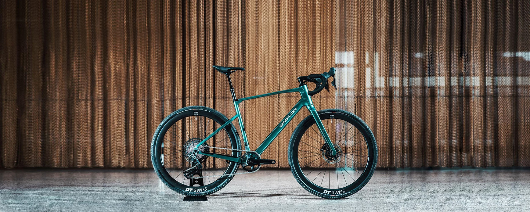 Tiefgrünes Gravelbike der vor HolzfassadeMarke Simplon