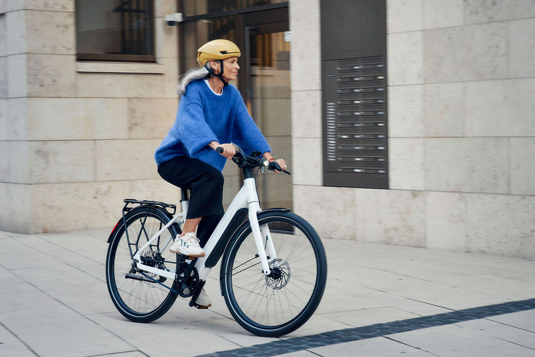 Frau fährt weißes Riese & Müller E-Bike durch die Stadt