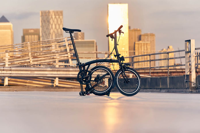 Schwarzes Brompton-Fahrrad auf Dach, Stadt im Hintergrund