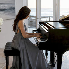 Pianist performing live on white grand piano indoors