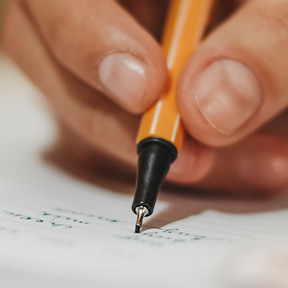 Photo d'une main qui écrit au stylo